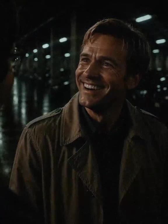 The man in the trench coat breaks into a grin.