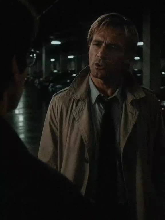 A man in a trench coat listens, unconvinced.